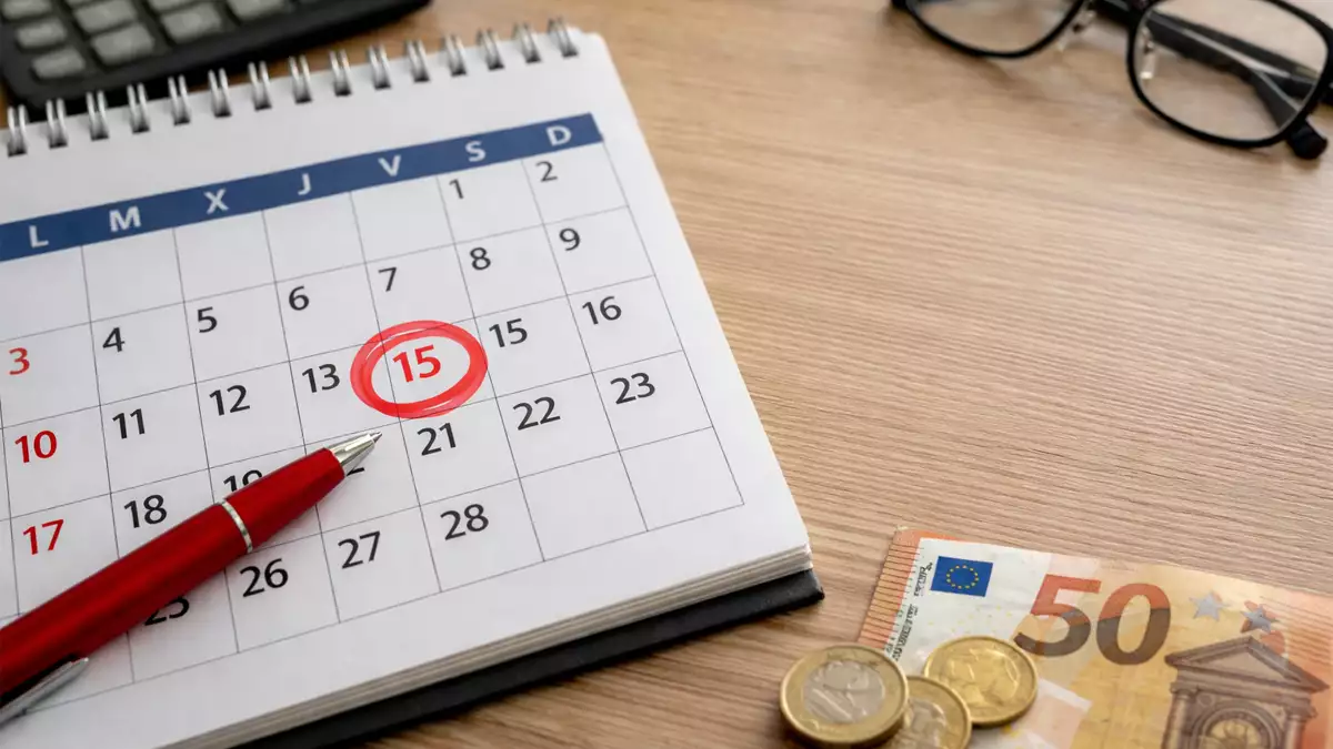 Calendario laboral con un día festivo marcado en rojo junto a dinero en euros