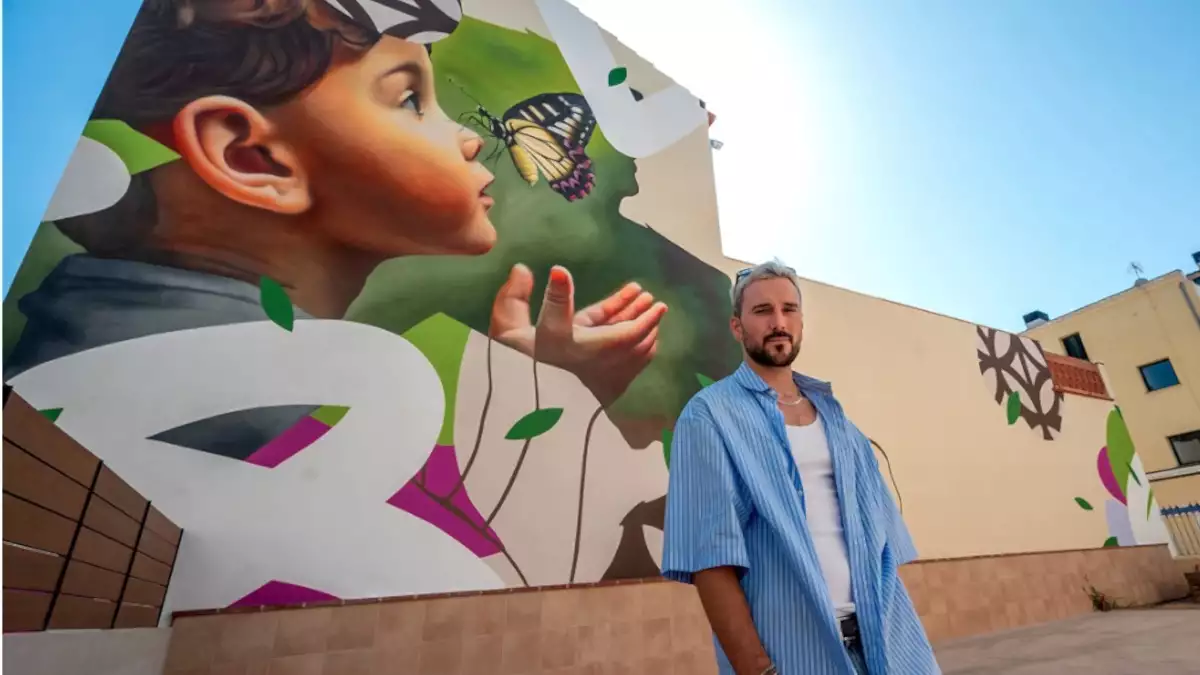 El artista DASE con uno de sus murales