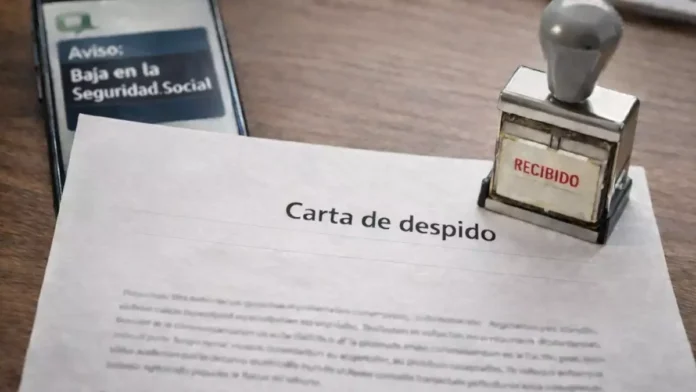 Carta de despido sobre una mesa junto a un móvil con aviso de baja en la Seguridad Social