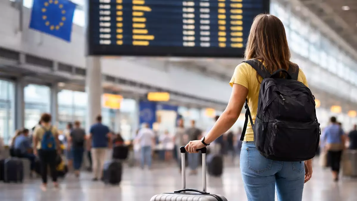 Estudiante universitario con maleta en aeropuerto antes de iniciar su estancia Erasmus con una beca Santander
