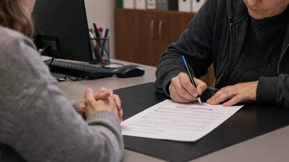 Trabajadora firmando un documento de baja voluntaria en una reunión con la empresa