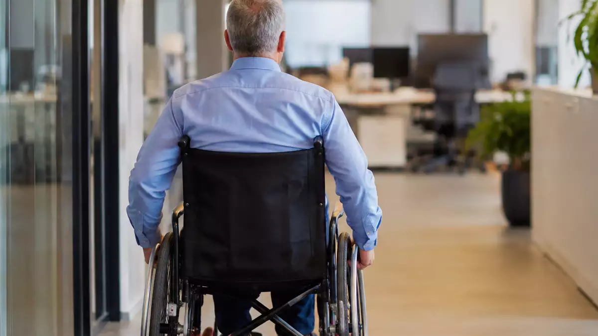 Trabajador de 56 años en silla de ruedas de espaldas en su lugar de trabajo