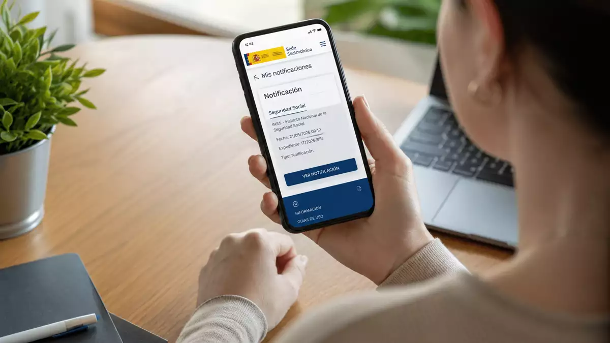 Persona consulta en su teléfono móvil una notificación electrónica de la Seguridad Social relacionada con una baja médica