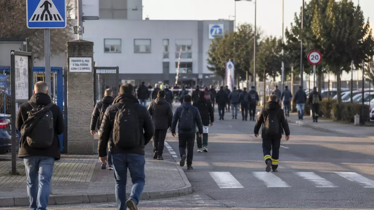 Trabajadores caminando hacia sus puestos de trabajo en una zona industrial de España.
