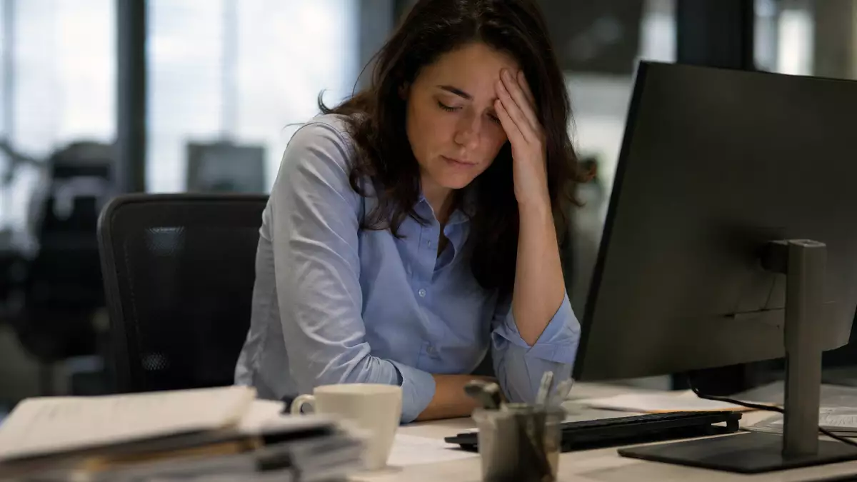 Trabajadora mostrando signos de agotamiento frente al ordenador durante su jornada laboral por una situación de burnout.