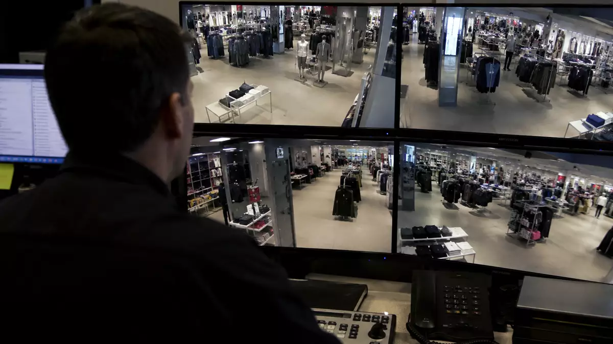 Monitores de videovigilancia mostrando el interior de una tienda de ropa mientras un responsable observa las imágenes.