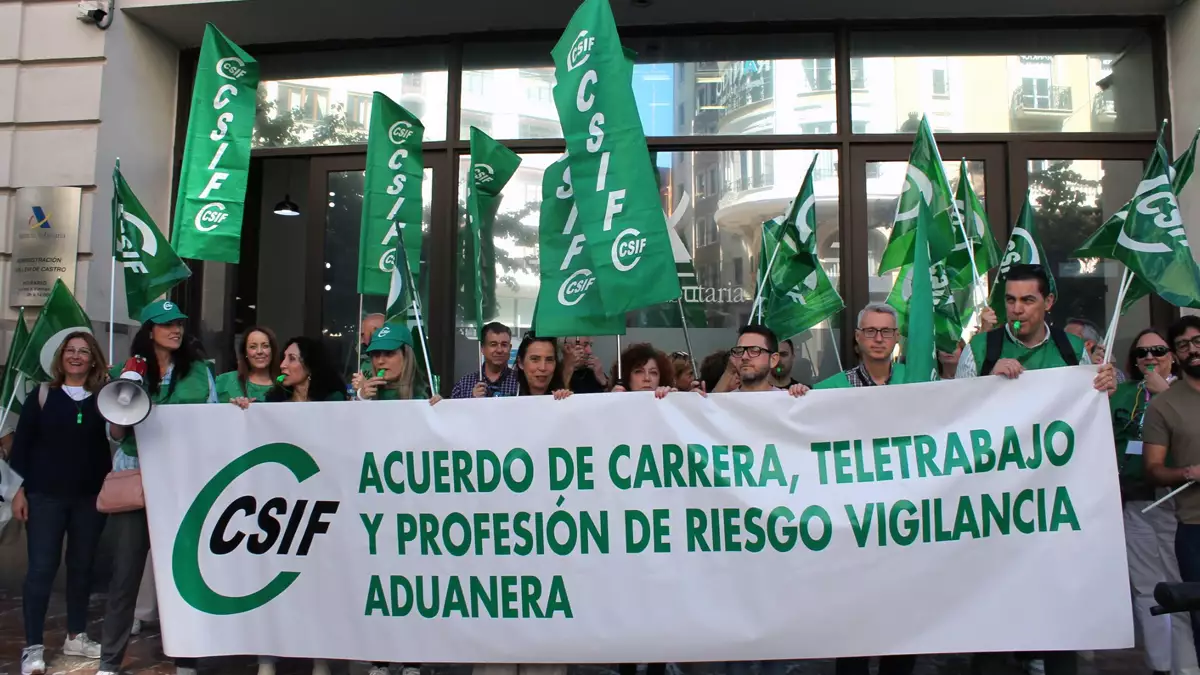 Group of protesters holding a large white banner with green text about a career and telework agreement, flanked by many green CSIF flags.