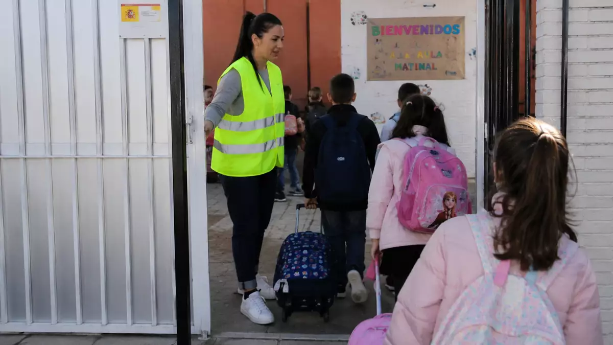 Monitor recibe a varios alumnos a la entrada de un centro educativo durante el servicio de aula matinal