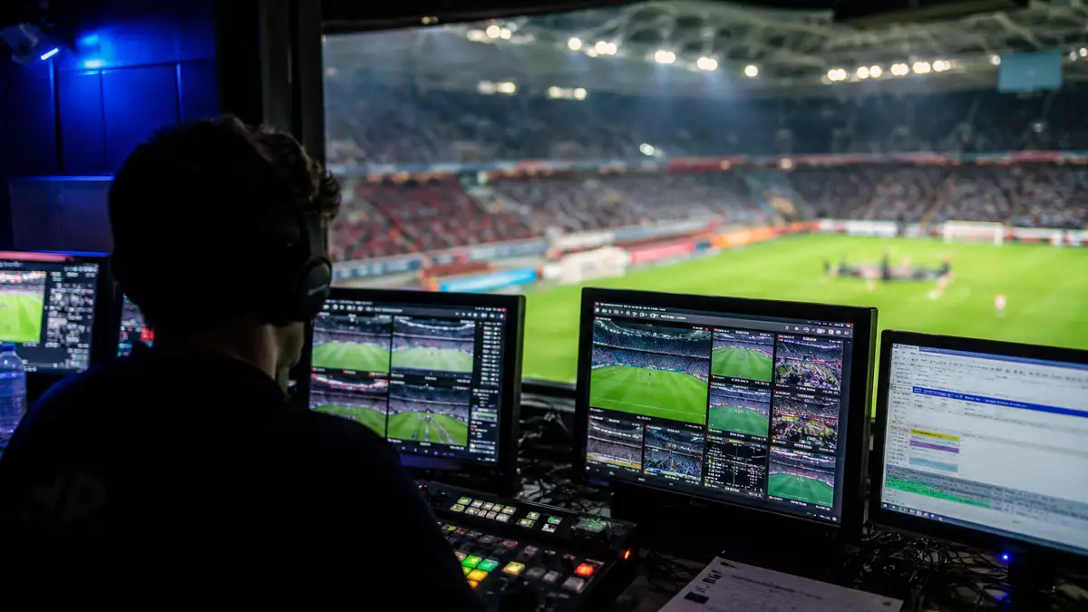 Operador de retransmisión deportiva trabajando con varios monitores durante un evento deportivo internacional