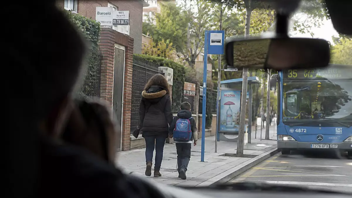 Trabajadora vigilada por un detective privado acompañando a un menor a la parada del autobús