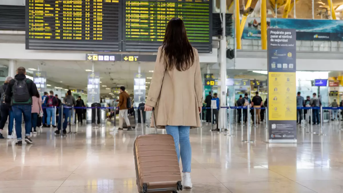 Persona con una maleta en un aeropuerto antes de viajar al extranjero mientras cobra el paro