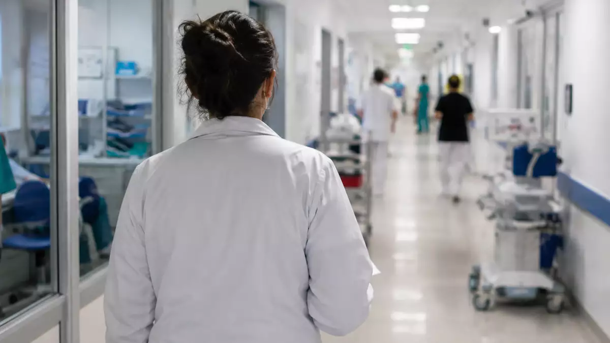 Representación generada con inteligencia artificial de una profesional sanitaria caminando por un hospital